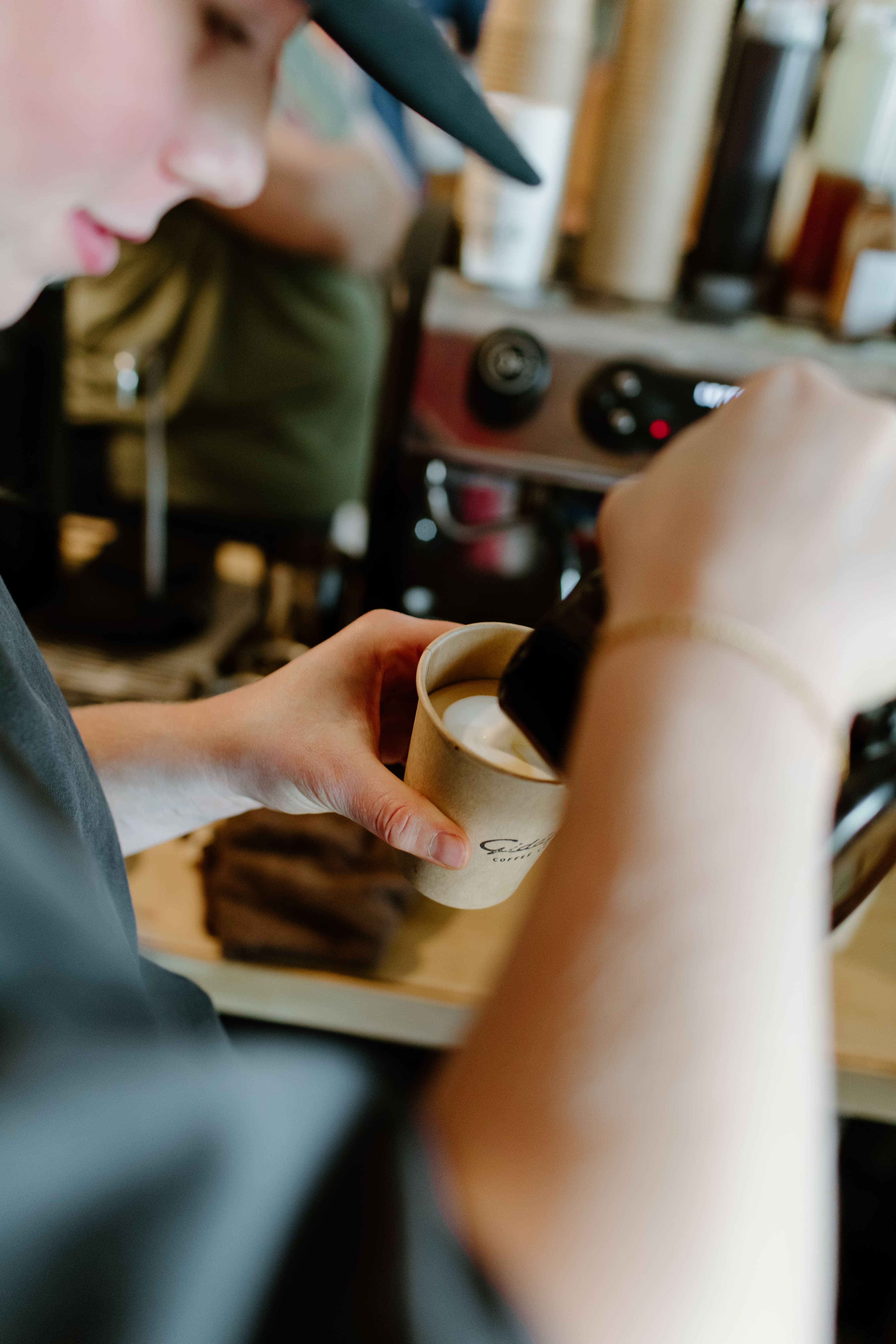 A friendly barista pouring smooth latte art at a coffee cart
